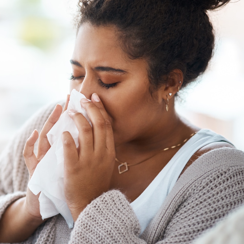 a woman uses a tissue to blow her nose